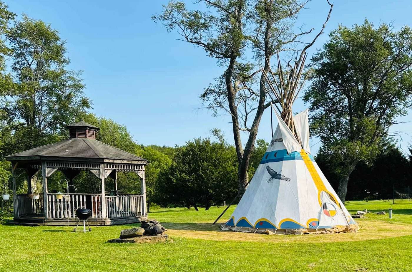 A painted canvas teepee on the lawn beside a white gazebo at Namaste Catskills